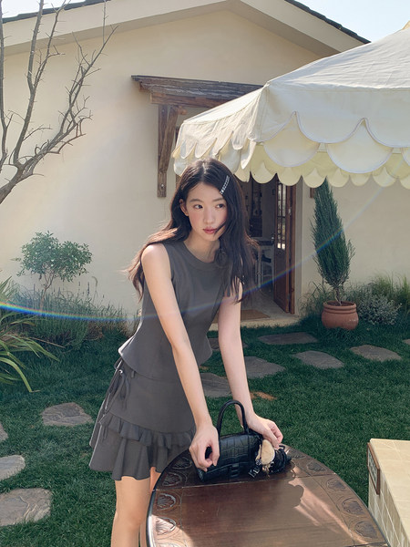 Woman wearing a gray sleeveless top and ruffled skirt set outdoors
