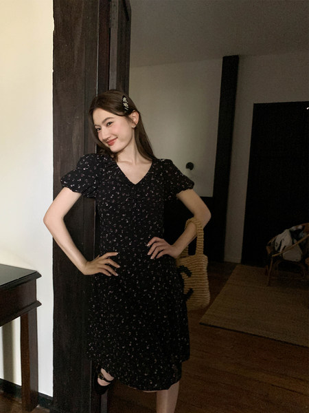 Woman wearing a black floral puff-sleeve dress indoors