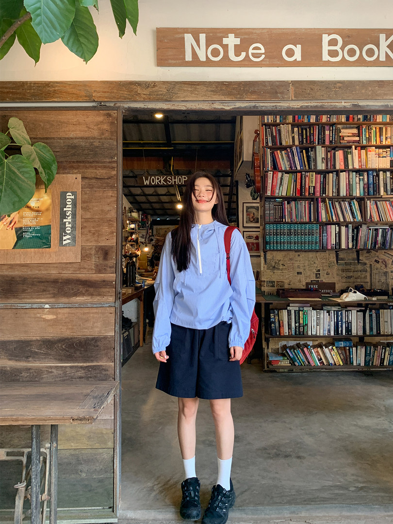 Woman wearing a light blue pullover top and navy shorts in a bookstore