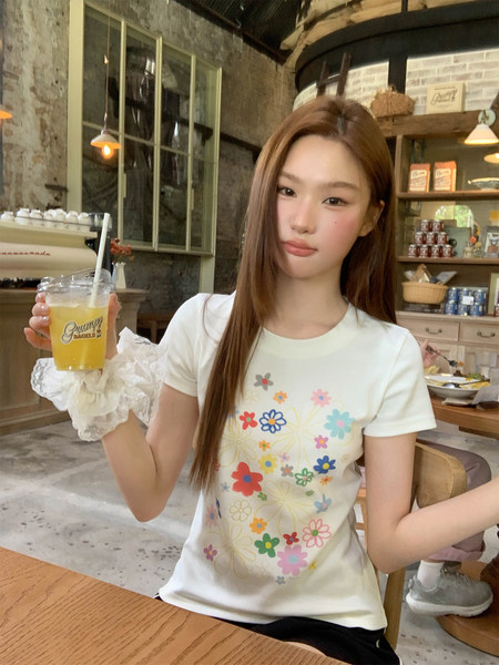 Woman wearing a white short-sleeve floral graphic T-shirt in a café