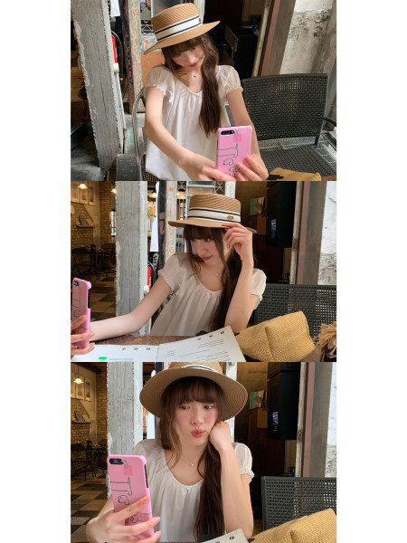 Woman wearing a straw sun hat and a white puff-sleeve blouse at a cafe