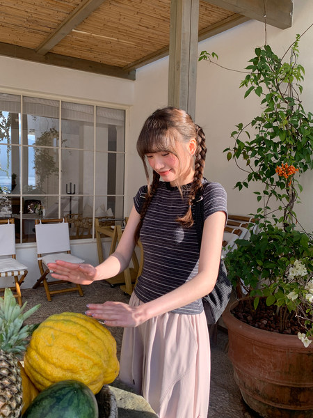 Woman wearing a striped short-sleeve top with a light pink skirt outdoors