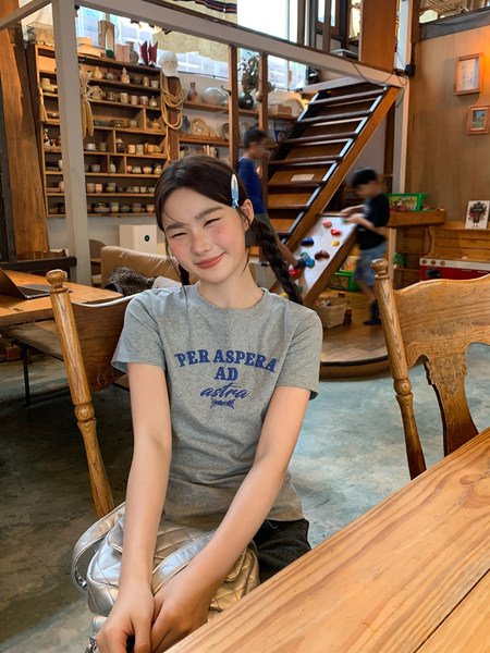 Gray graphic T-shirt worn by a smiling woman indoors
