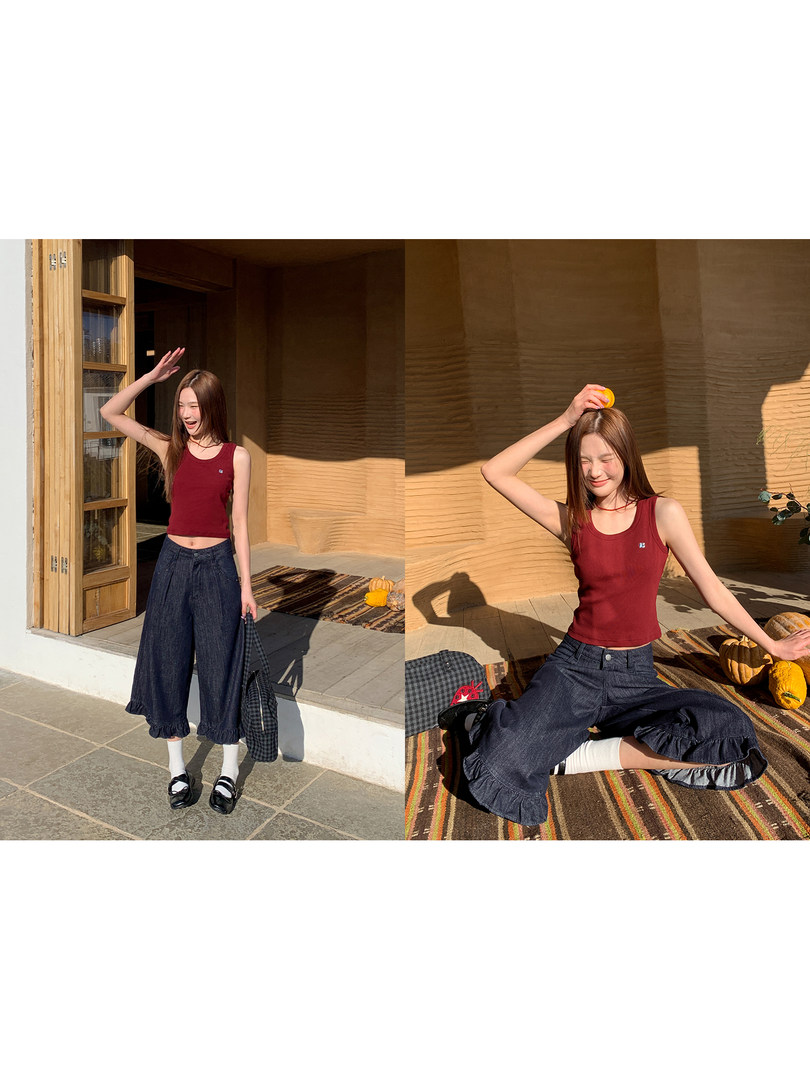 Model wearing a burgundy sleeveless tank top with wide-leg dark denim pants