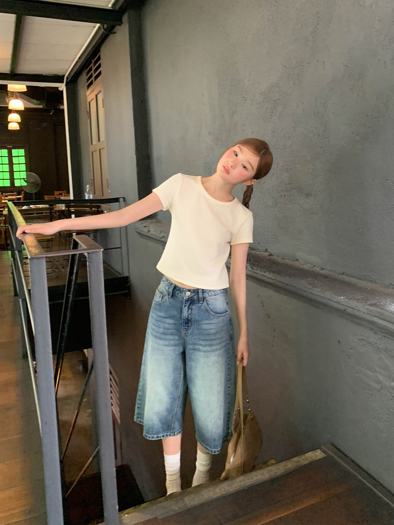 Model wearing a white short-sleeve t-shirt with wide-leg denim shorts