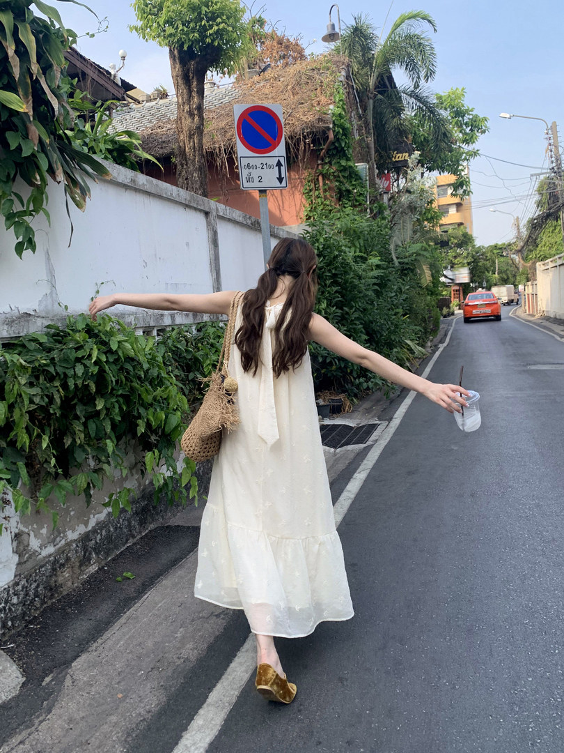 Woman wearing a long cream sleeveless dress outdoors