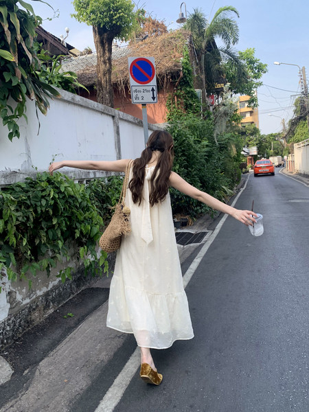 Woman wearing a long cream sleeveless dress outdoors
