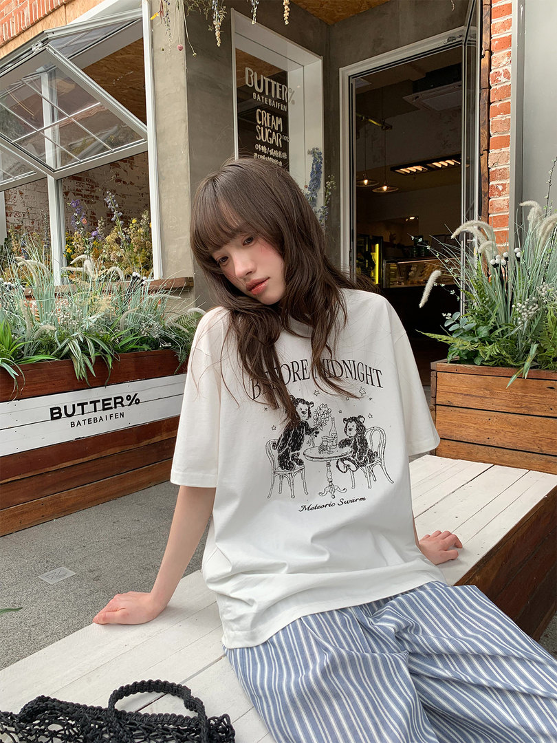 Model wearing a white graphic T-shirt and blue striped pants outdoors