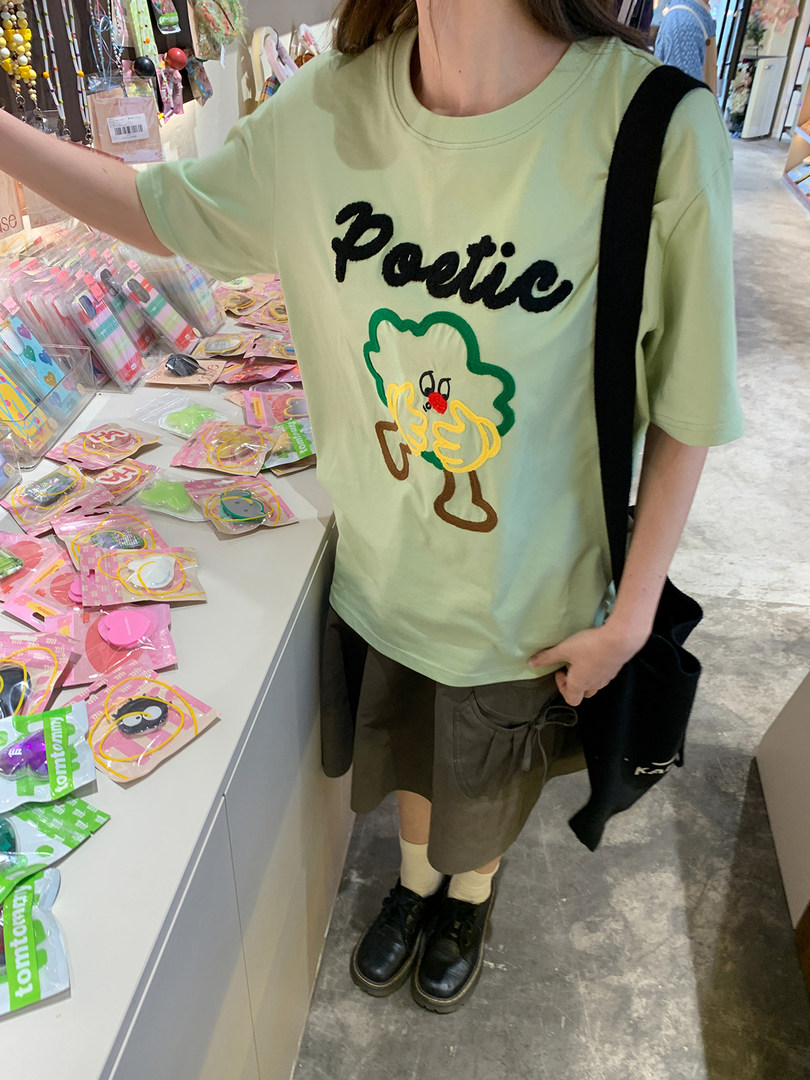 Light green graphic T-shirt worn with an olive skirt