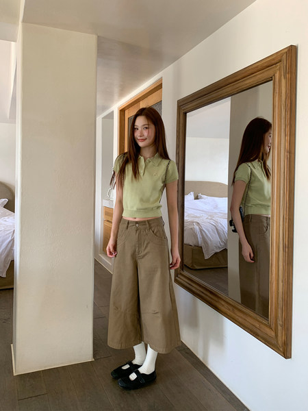 Woman wearing a light green polo top with wide-leg khaki pants