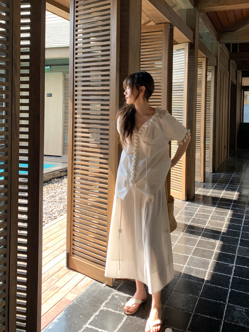 Woman wearing a white feminine dress in a resort-style setting