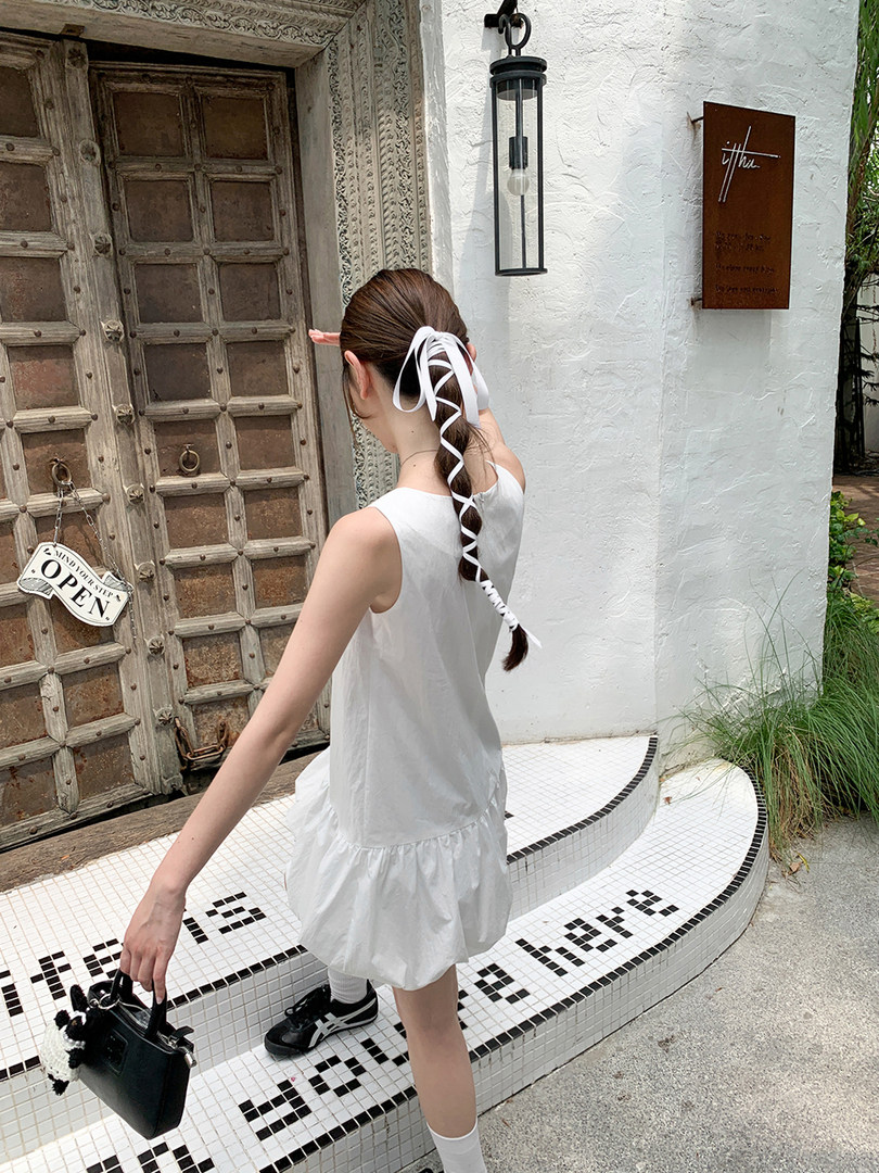 White sleeveless dress worn by a model outdoors