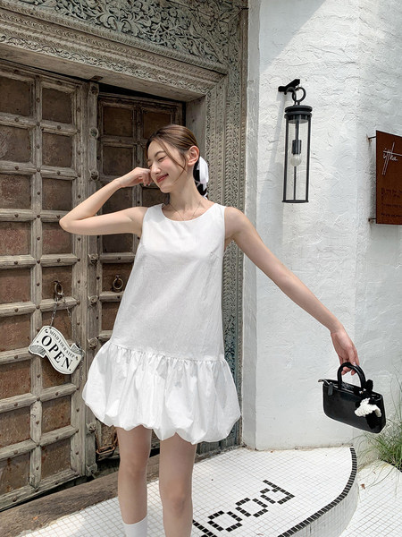 Woman wearing a white sleeveless mini dress with a puffed hem