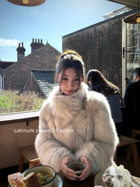 Model wearing a fluffy light gray fur coat at a cafe