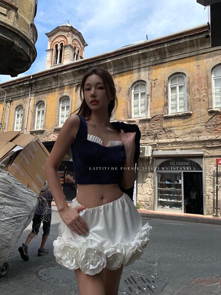 Woman wearing a navy crop top and white floral mini skirt outdoors