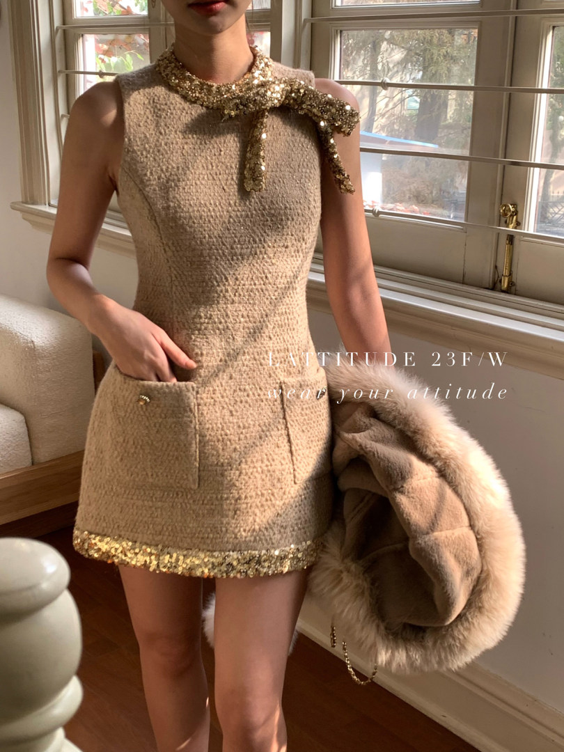 Model wearing a beige sequined sleeveless mini dress with bow detail