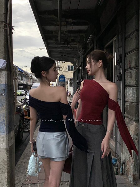 Two women wearing off-shoulder fitted tops with skirts on a street