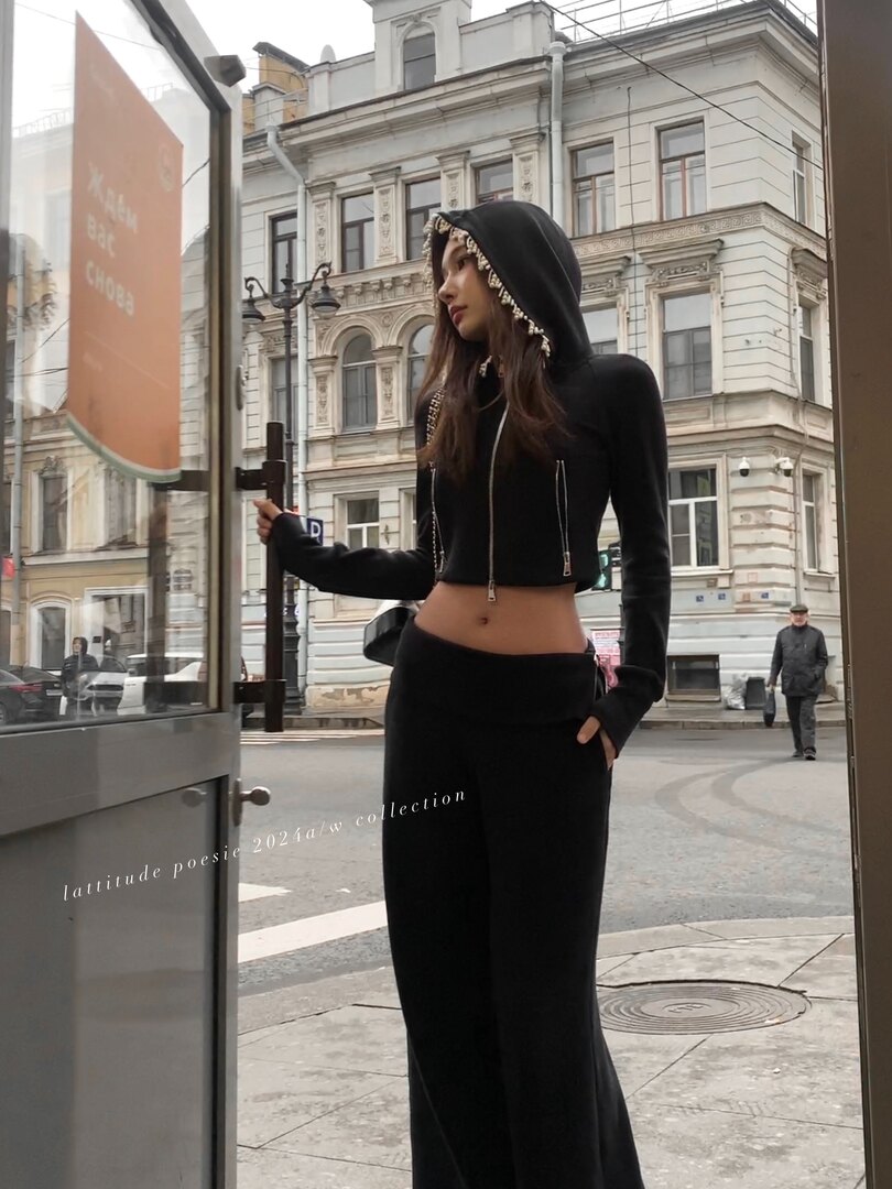 Woman modeling a black hooded cropped top and wide-leg pants outdoors