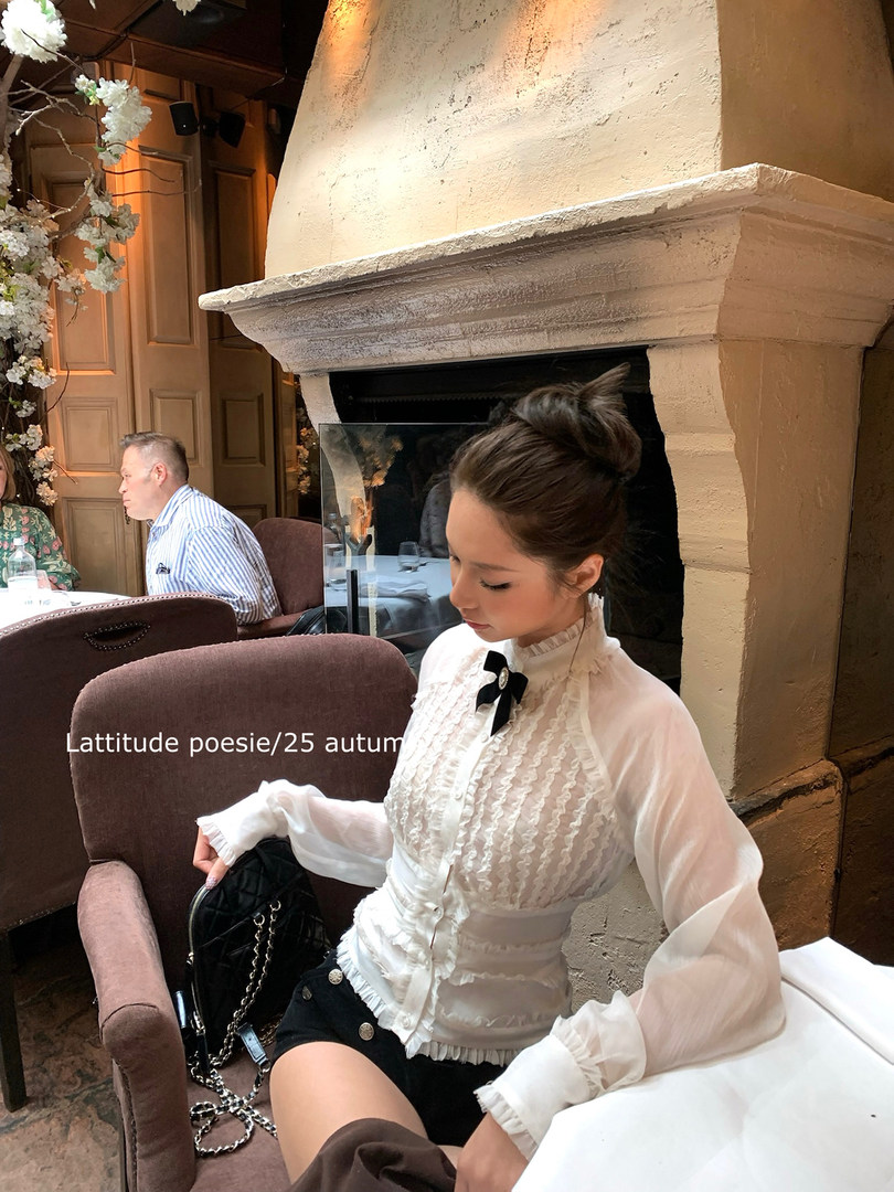 Woman wearing a white ruffled blouse and black shorts in a restaurant setting