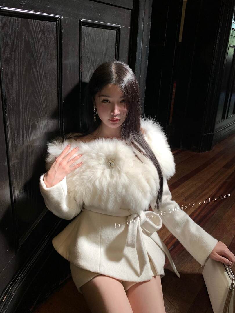 Woman wearing a white fur-trimmed coat with a tied waist belt