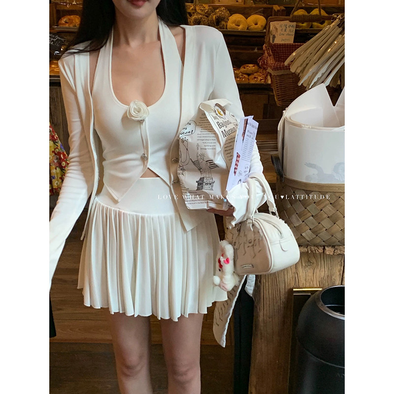 Woman wearing a white pleated dress set with a matching small handbag