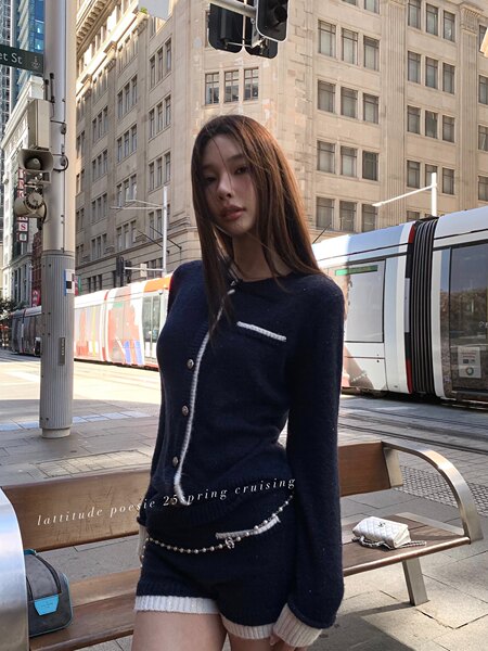 Model wearing a navy knit cardigan-style top with white trim on a city street