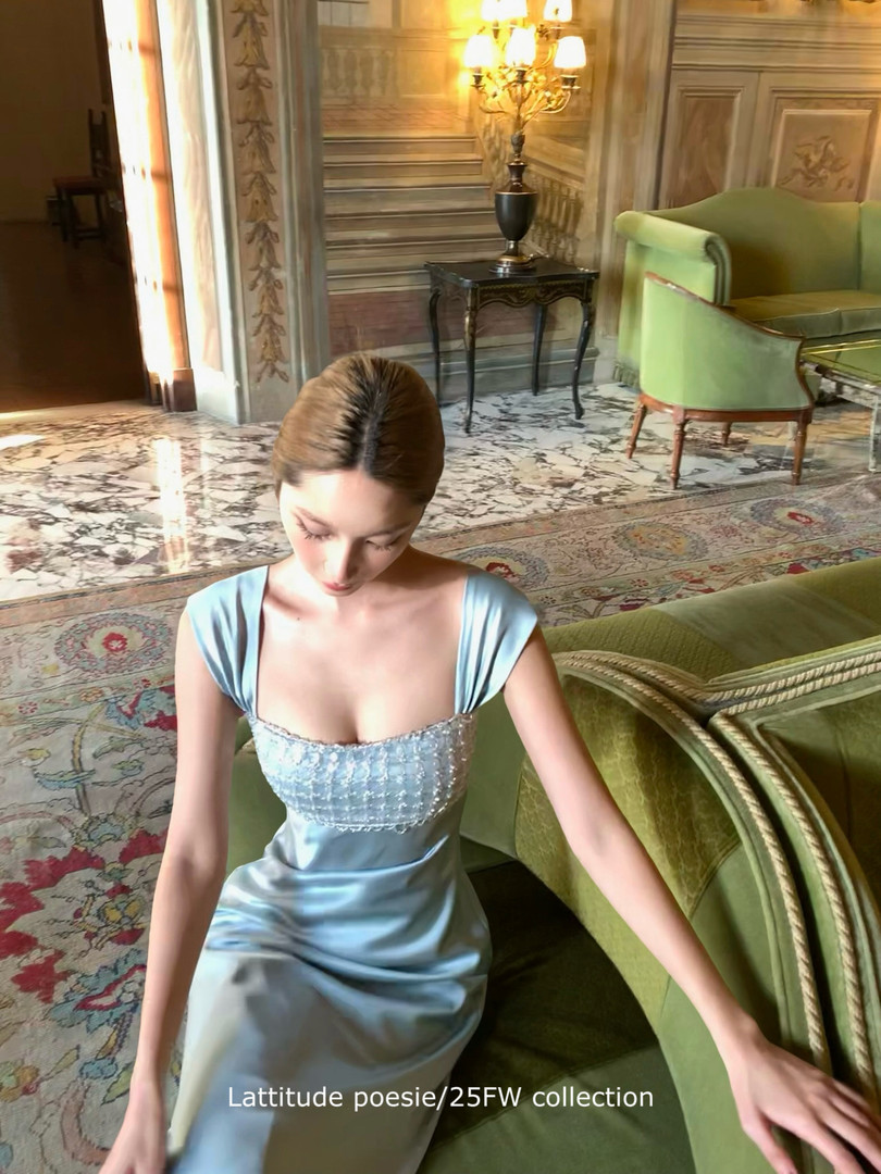 Light blue satin evening dress worn by a model in an ornate interior