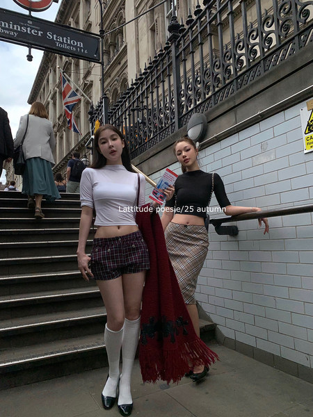 Two women modeling plaid skirts and fitted crop tops on outdoor steps