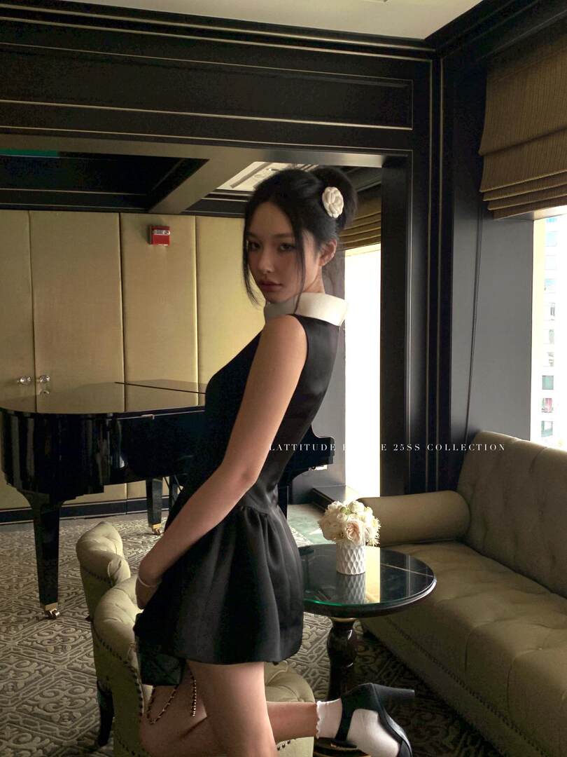 Black sleeveless mini dress worn by a model in an elegant indoor setting