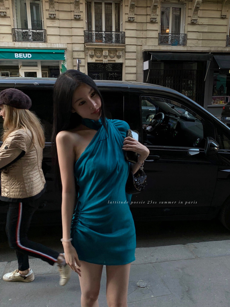 Teal halter mini dress worn by a model on a city street
