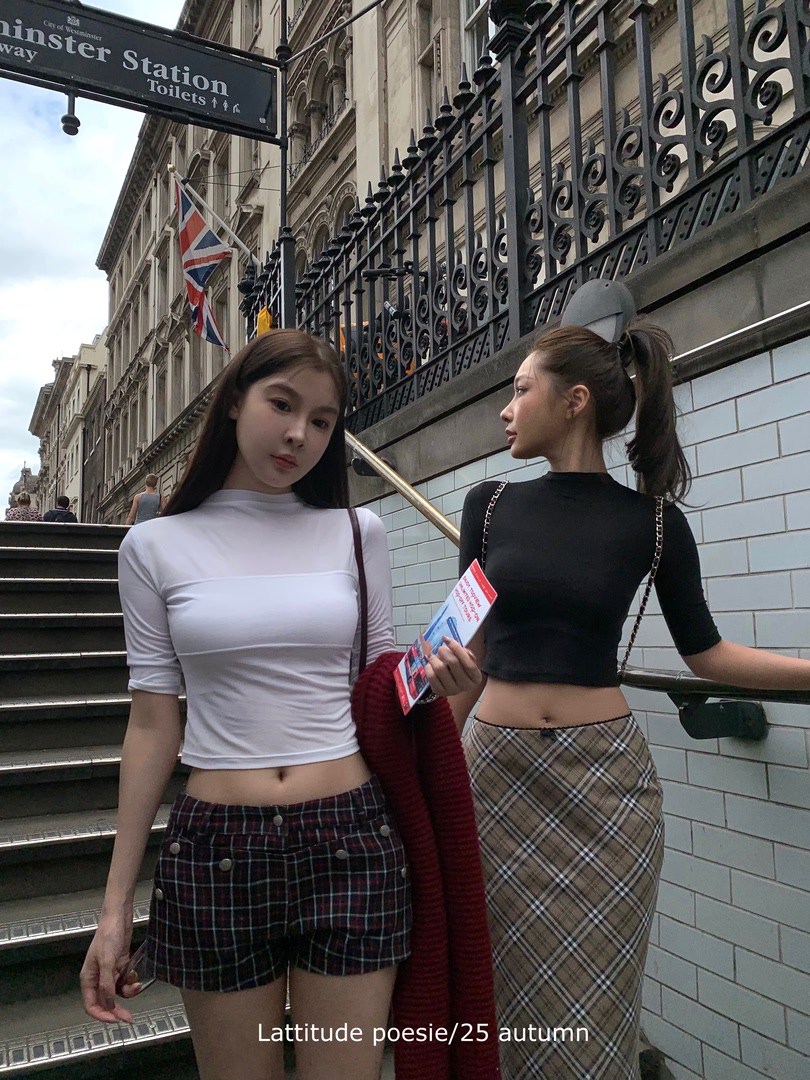 Two women wearing autumn streetwear outfits with fitted tops and plaid skirts