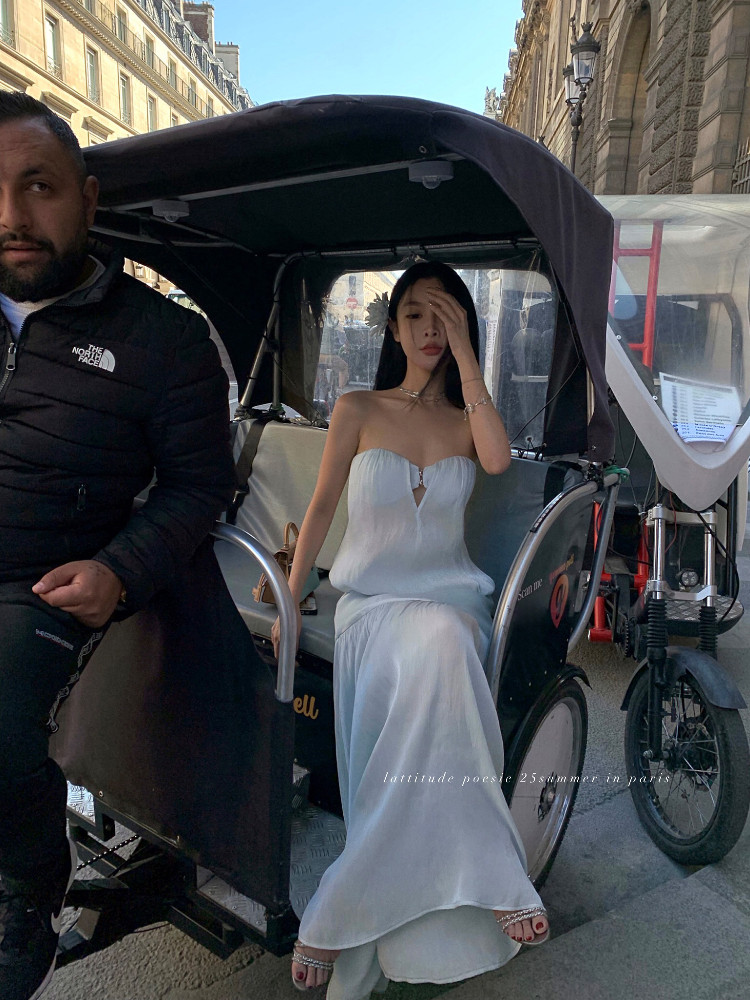 Woman wearing a white strapless maxi dress sitting in a rickshaw