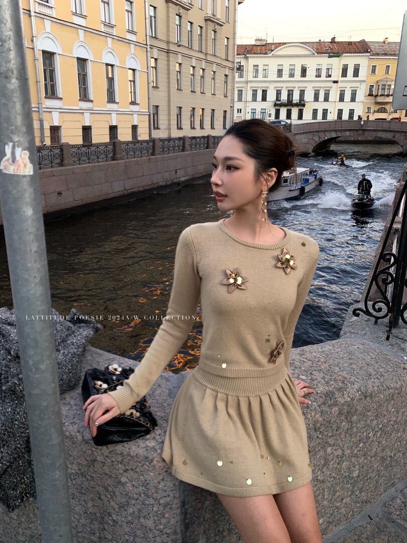 Beige long-sleeve knit dress worn by a woman outdoors by a canal