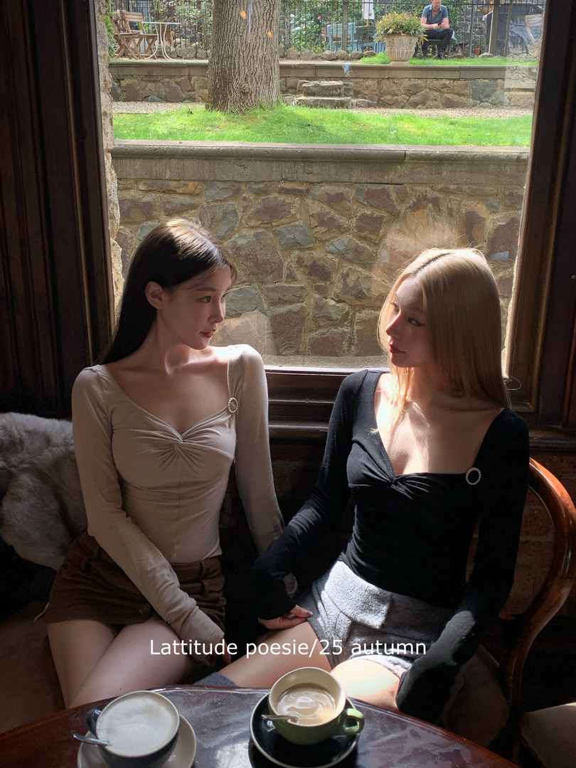 Two women wearing fitted long-sleeve tops and skirts in a cafe