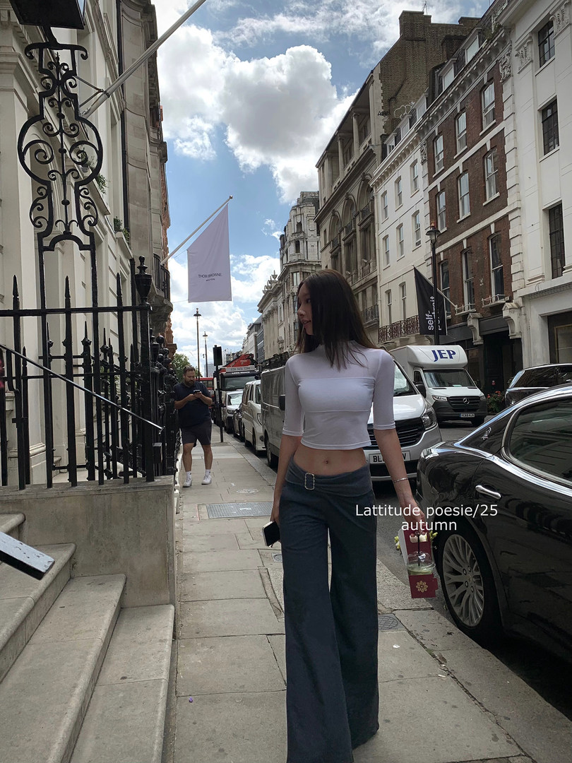Woman wearing a white fitted crop top and dark wide-leg pants on a city street