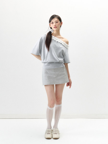 Model wearing a light gray off-shoulder top and matching mini skirt with white socks and shoes