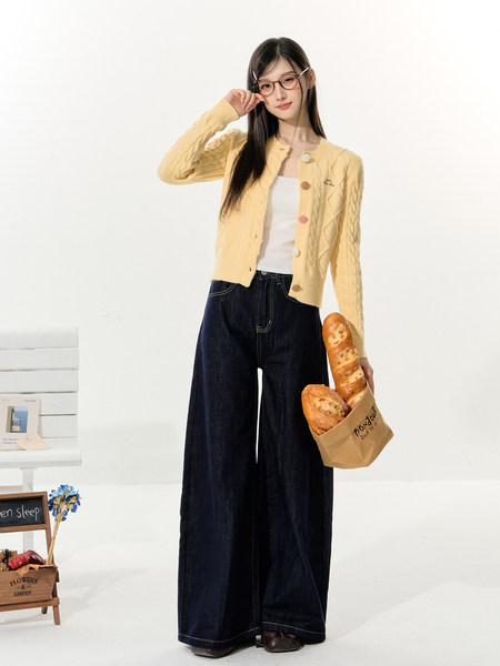 Model wearing a pale yellow cable-knit cardigan with dark wide-leg jeans