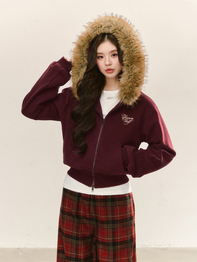 Model wearing a burgundy zip hoodie with a fur-trim hood and plaid pants