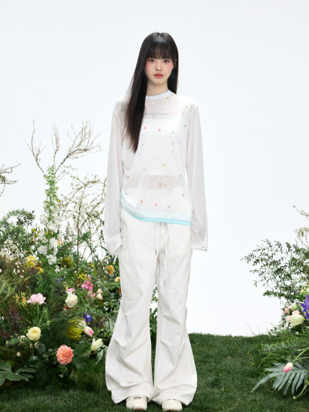 Model wearing a white long-sleeve top and wide-leg pants with pastel star print