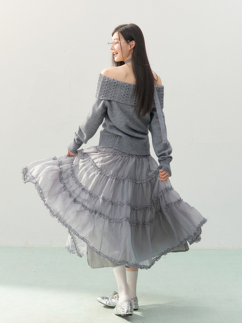 Woman wearing a gray off-shoulder knit sweater with a layered ruffle skirt