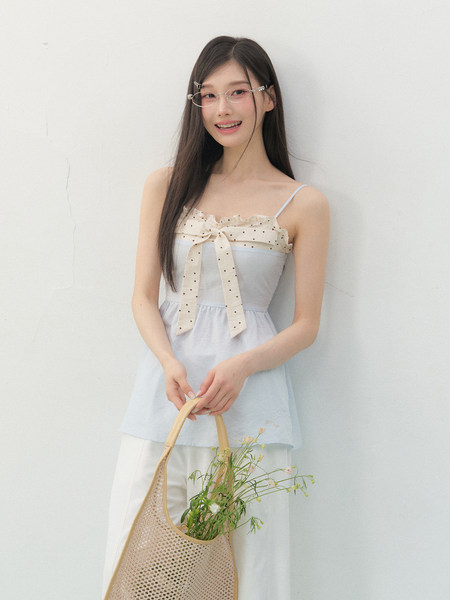 Model wearing a light blue sleeveless dress with a polka dot bow detail