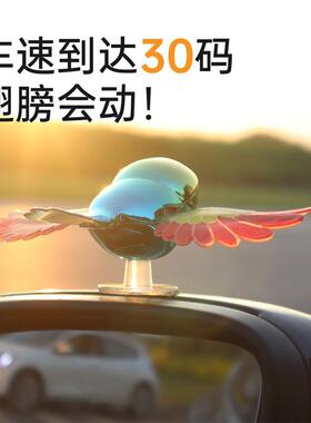 A car with a cute ornament and a little birds helmet with a