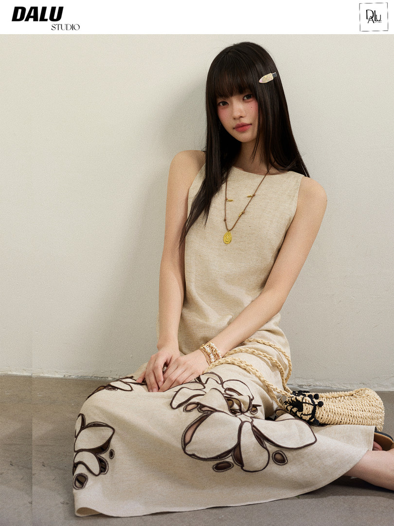 Model wearing a sleeveless beige dress with floral embroidery