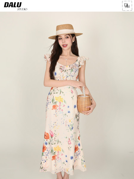Floral sleeveless midi dress worn by a model with a straw hat and wicker bag