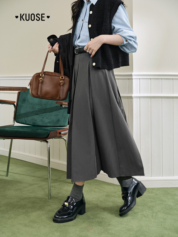 Woman wearing a preppy office-style outfit with a brown handbag and black loafers