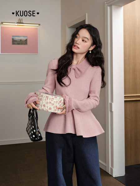 Model wearing a pink knit peplum sweater top with dark pants
