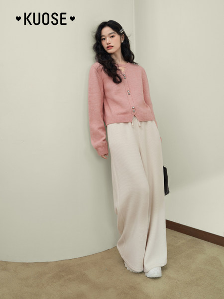 Model wearing a pink cardigan with cream wide-leg pants