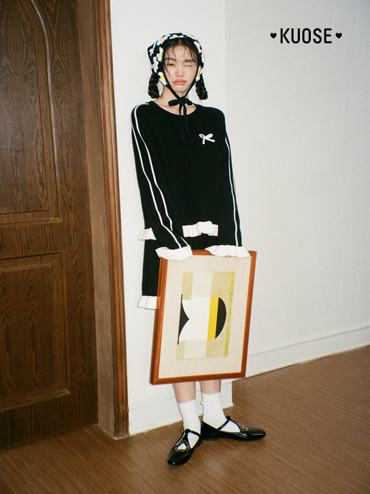 Black long-sleeve dress with white striped sleeves and ruffled cuffs worn by a model