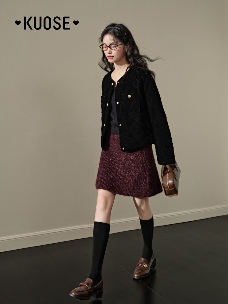 Model wearing a black jacket with a burgundy skirt and loafers