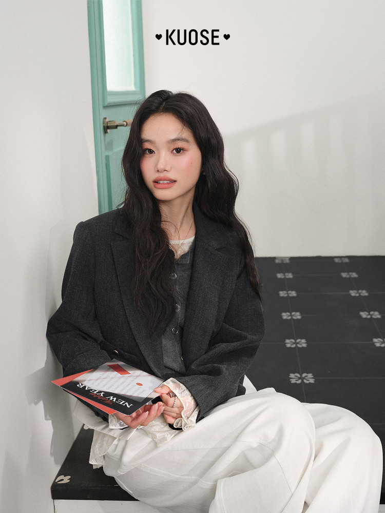 Model wearing a dark charcoal blazer with white pants